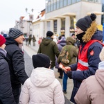 Białostoczanie z dziećmi wrzucają pieniądze do kolorowej puszki Wielkiej Orkiestry Świątecznej Pomocy 