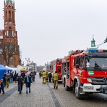 Dwa wozy strażackie stoją na Rynku Kościuszki, obok przechadzają się strażacy oraz białostoczanie