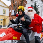 Kolorek oraz wolontariusz przebrany w strój Mikołaja siedzą na czerwonym skuterze WOPR