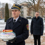 Zastępca prezydenta Rafał Rudnicki podąża w stronę pomnika w asyście strażnika miejskiego trzymającego w dłoni znicz