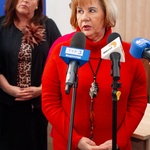 Kobieta udziela wywiadu stojąc przed mikrofonami, w tle inni uczestnicy konferencji