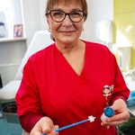 Pielęgniarka udziela wywiadu do mikrofonu i w rękach trzyma fiolkę oraz sondę.