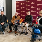Uczestnicy konferencji prasowej siedzą na krzesłach.