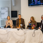 Pięciu uczestników konferencji prasowej siedzi przy stole, koordynatorka festiwalu Dni Sztuki Współczesnej Katarzyna Kruszewska mówi do mikrofonu.
