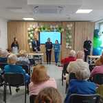 Na zdjęciu przedstawiciele urzędu miejskiego i straży miejskiej przed siedzącymi seniorami. Trwa wykład