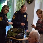 strażnicy miejscy pokazują seniorom zawartość plecaka ewakuacyjnego