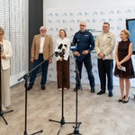 Uczestnicy konferencji stoją, prowadząca Eliza Bilewicz-Roszkowska mówi do mikrofonu.