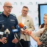 Rzecznik prasowy wojewódzkiej Komendy Policji w Białymstoku Tomasz Krupa mówi do mikrofonu.