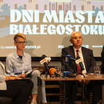 Kobieta mówi do mikrofonów podczas konferencji prasowej, obok siedzą przedstawiciele Miasta.