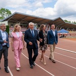 Uczestnicy konferencji prasowej idą po korcie stadionu.
