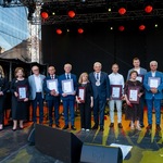 Nagrodzeni odznaczeniem Urbi Meritus stoją na scenie pozując do wspólnego zdjęcia.