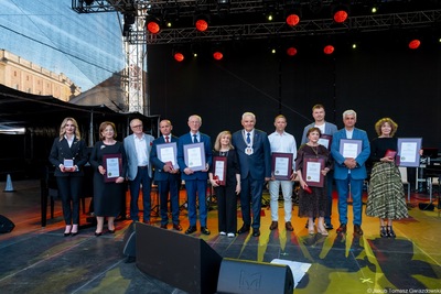 Odznaczeni przez prezydenta stoja na scenie pozując do wspólnego zdjęcia.