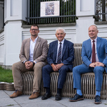 Uczestnicy konferencji prasowej siedzą na ławce 