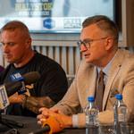 Zastępca prezydenta Rafał Rudnicki siedzi przy stole z innymi uczestnikami podczas konferencji prasowej.