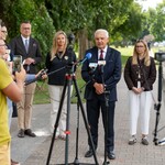 Prezydent Tadeusz Truskolaski udziela wywiadu, w tle stoa inni uczestnicy konferencji prasowej.