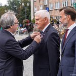 Mężczyzna przypina do klapy marynarki prezydenta Tadeusza Truskolaskiego odznaczenie.