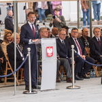 Przedstawiciele instytucji siedzą podczas uroczystości, na pierwszym planie wojewoda Jacek Brzozowski mówi do mikrofonu.