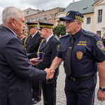 Prezydent Tadeusz Truskolaski podaje dłoń funkcjonariuszowi Straży Miejskiej podczas uroczystości.