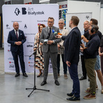 Zastępca prezydenta Rafał Rudnicki udziela wywiadu, w tle stoją inni uczestnicy konferencji prasowej.