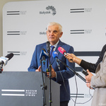 Prezydent Tadeusz Truskolaski mówi do mikrofonów podczas konferencji prasowe, obok stoją dziennikarze.