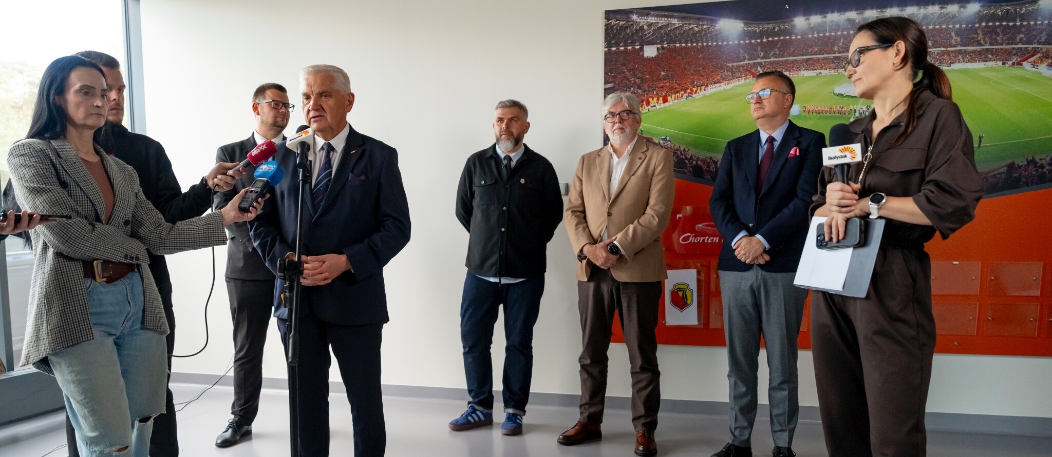 Prezydent Tadeusz Truskolaski udziela wywiadu podczas konferencji prasowej, obok stoją inni uczestnicy oraz dziennikarze.