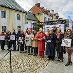 Uczestnicy konferencji prasowej stoją przed mikrofonem.