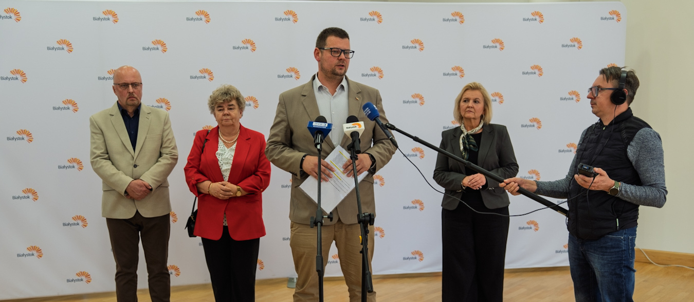 Zastępca prezydenta Tomasz Klim mówi do mikrofonów podczas konferencji prasowej, w tle stoją inni uczestnicy.