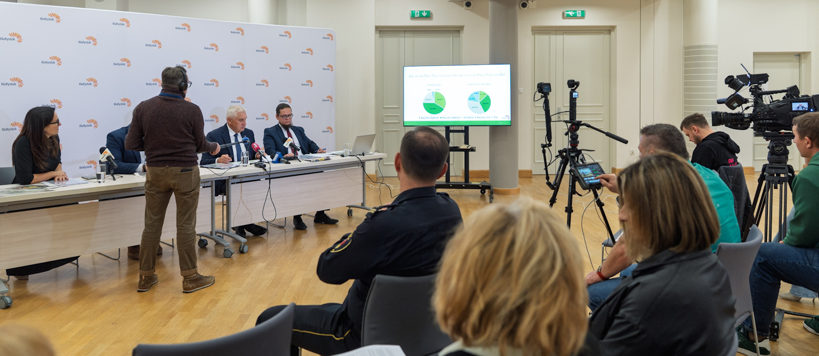 Uczestnicy konferencji prasowej siedzą w dużej sali podczas spotkania.