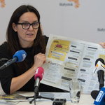 Dyrektor Departamentu Komunikacji Społecznej Urszula Boublej trzyma otwartą gazetę podczas konferencji prasowej.