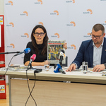 Przedstawiciele Miasta siedzą przed mikrofonami podczas konferencji prasowej.