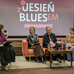Uczestnicy konferencji prasowej siedzą na kanapie, obok siedzi prowadząca z mikrofonem.