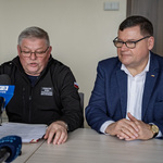 Zastępca prezydenta Marek Masalski oraz mężczyzna siedzą przed mikrofonami podczas konferencji prasowej.