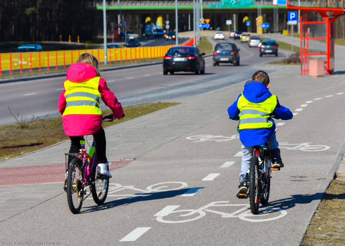 Dzieci na rowerach jadą po ścieżce rowerowej